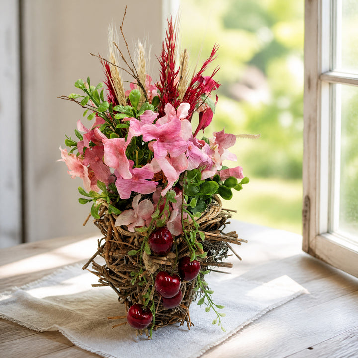 Szene Sommergesteck Kirschen Blüten Gräser rosa rot im Zweiggeflecht