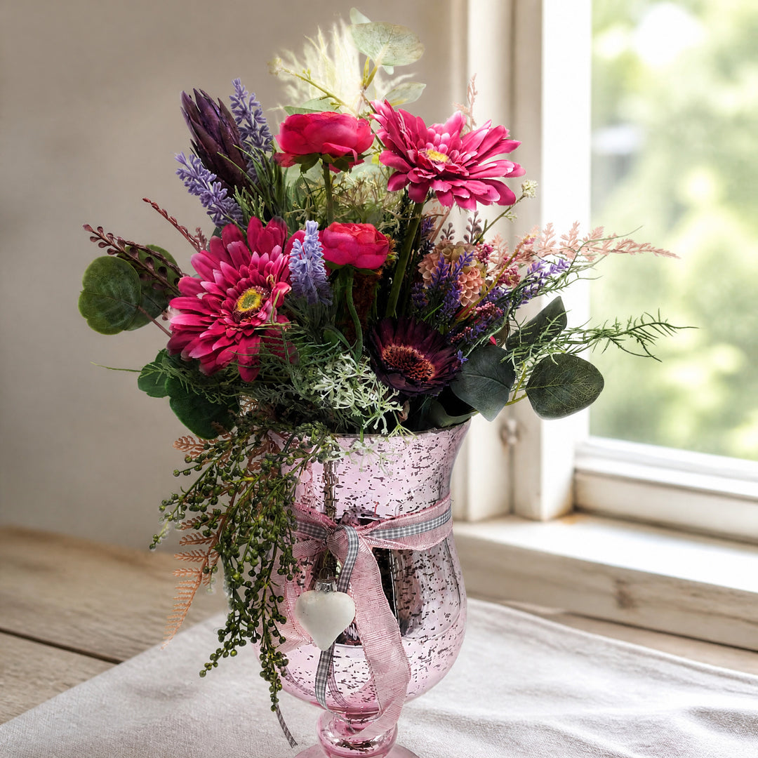 Szene Sommergesteck Gerbera Ranunkel Farn rosa lila im Glaspokal