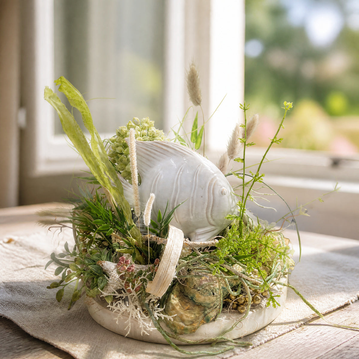 Szene Sommergesteck maritim Keramikfisch Gräser Muscheln grün creme