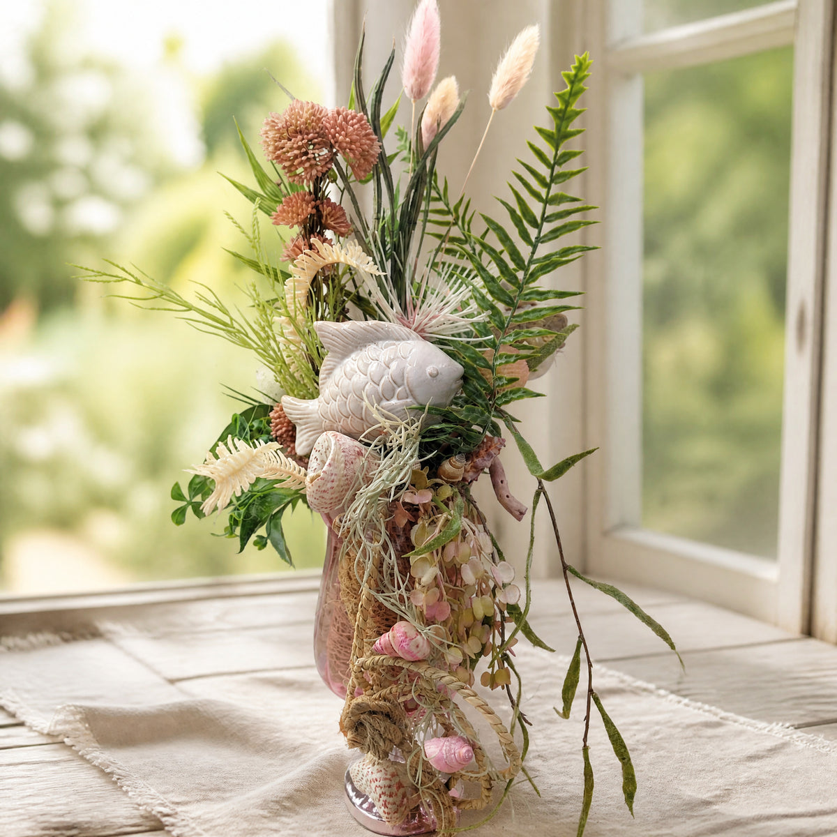 Szene Sommergesteck Fisch Muscheln Gräser Sedum maritim rosa
