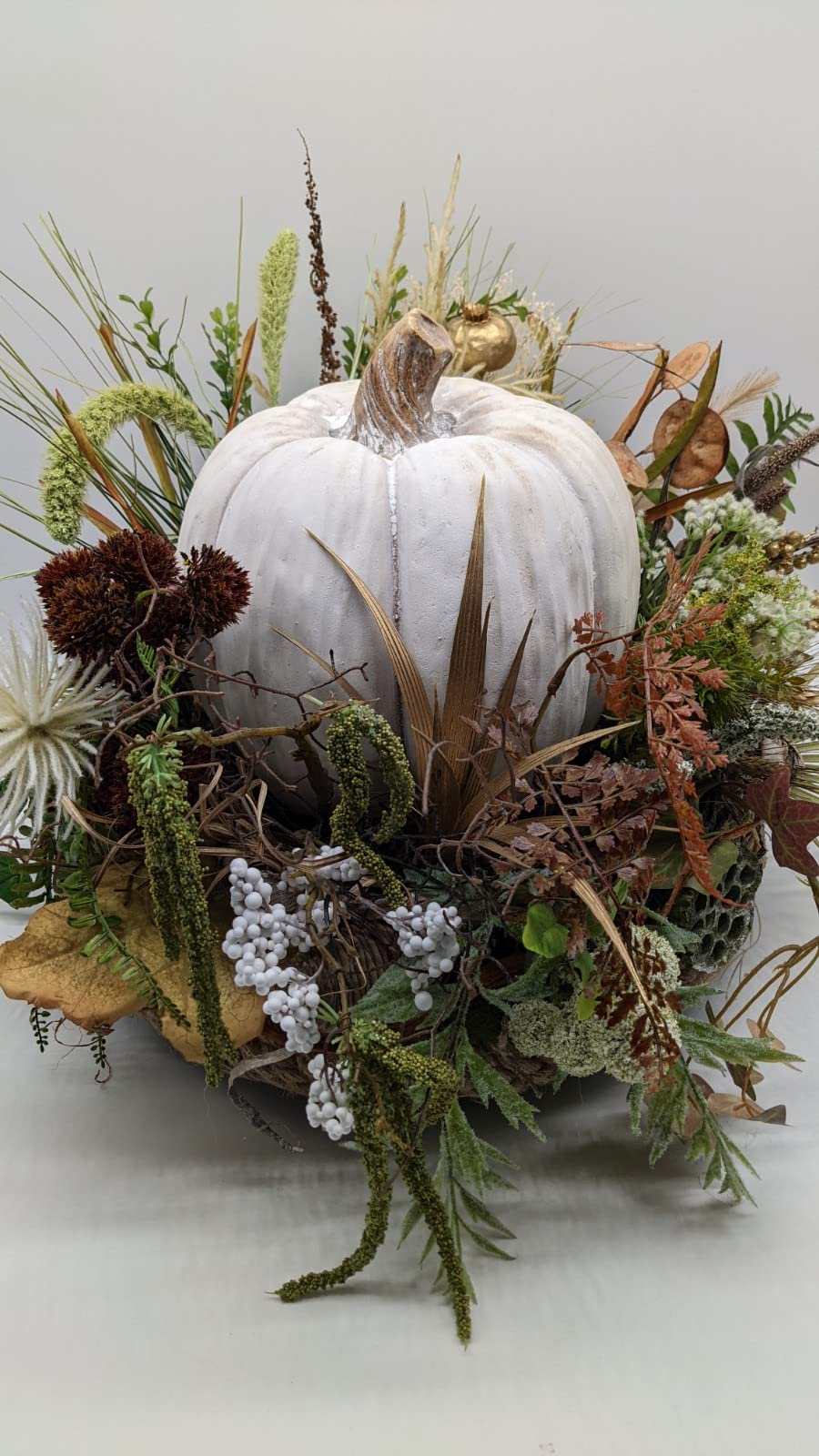Herbstgesteck von vorn: weißer Kürbis mit goldenem Mini-Kürbis, Farn, Efeu, Gräsern und Palmblättern