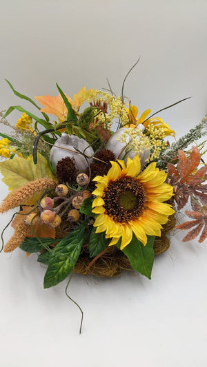 Herbstgesteck von der Seite mit orangefarbenem Ahornlaub, braunen Gräsern, Beerendolden und Sonnenblume
