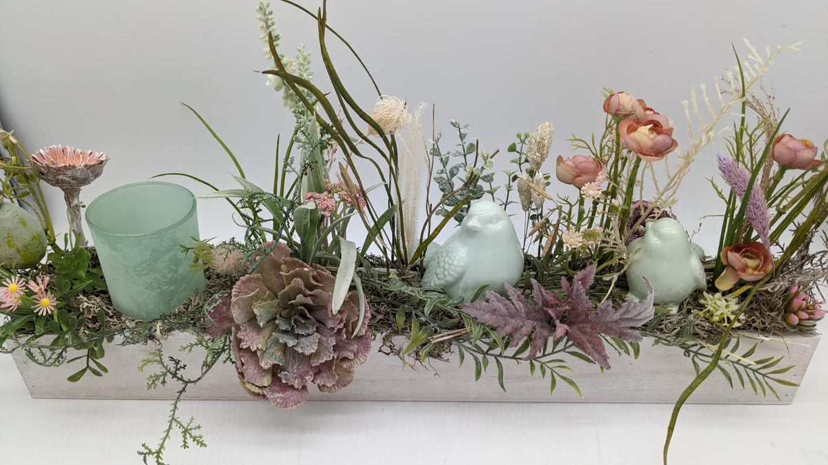 Tischgesteck in Mint und Rosa mit Ranunkeln, Gänseblümchen, Altrosa-Blüte, Farn und Moos im flachen Holzkasten