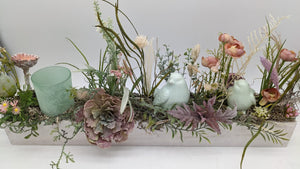 Tischgesteck in Mint und Rosa mit Ranunkeln, Gänseblümchen, Altrosa-Blüte, Farn und Moos im flachen Holzkasten