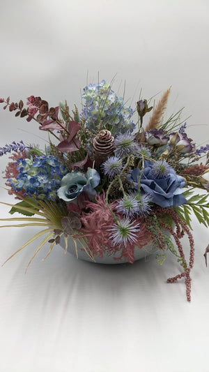 Flache Schale mit blaugrauen Rosen, lila Disteln, altrosa Farn und herabhängenden rosa Beerenketten