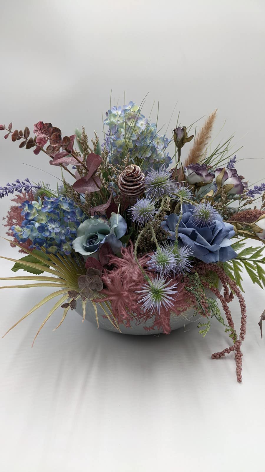 Flache Schale mit blaugrauen Rosen, lila Disteln, altrosa Farn und herabhängenden rosa Beerenketten