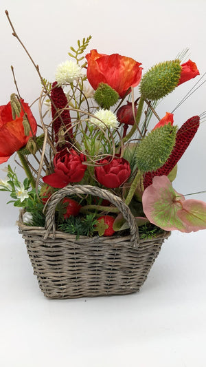 Seitenansicht des Korbgestecks mit Mohnblüten, Erdbeeren, dunkelroten Kolben und rosé-grünem Anthurienblatt