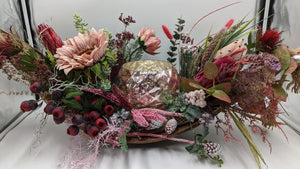 Langes Herbstgesteck in Holzschale mit rosé schimmerndem Windlicht, altrosa Sonnenblume, roten Beeren und Zapfen