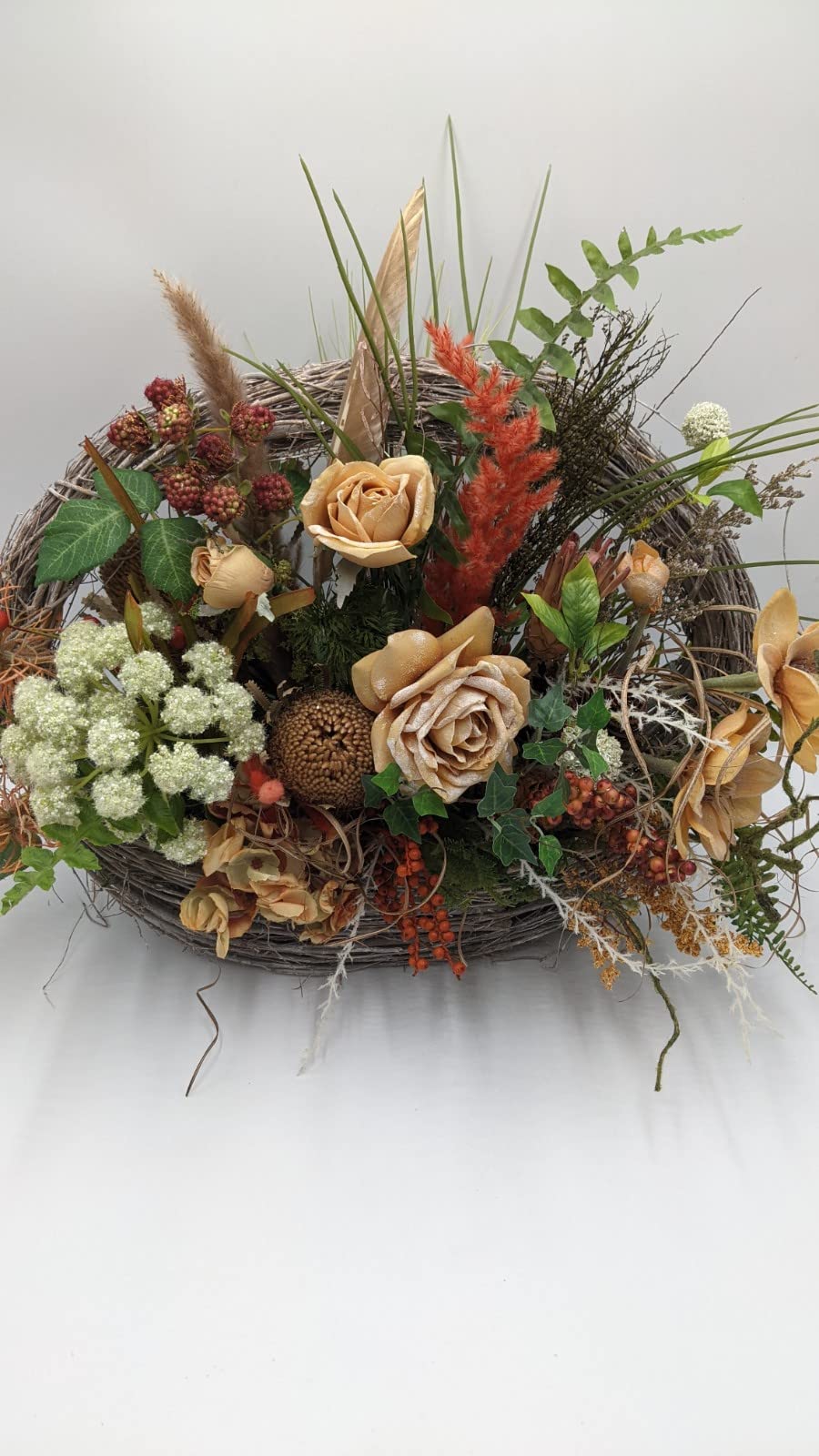 Breites Herbstgesteck von vorn: Rosen in Apricot, weiße Dolde, Efeu, rote Brombeeren und orange Federähre