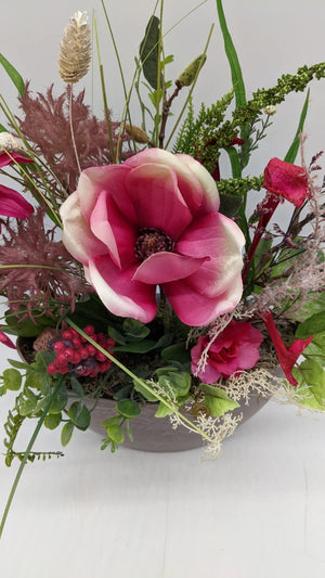 Nahaufnahme der pinken Magnolienblüte mit cremefarbenen Rändern, Beerendolde und Eukalyptus im Gesteck