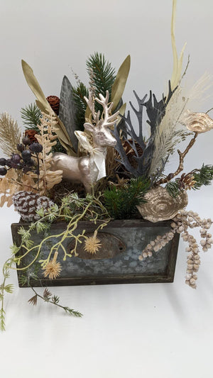Wintergesteck in Metallschublade mit Hirschfigur, Tannenzweigen, Zapfen, dunklen Beeren und goldenen Scheiben