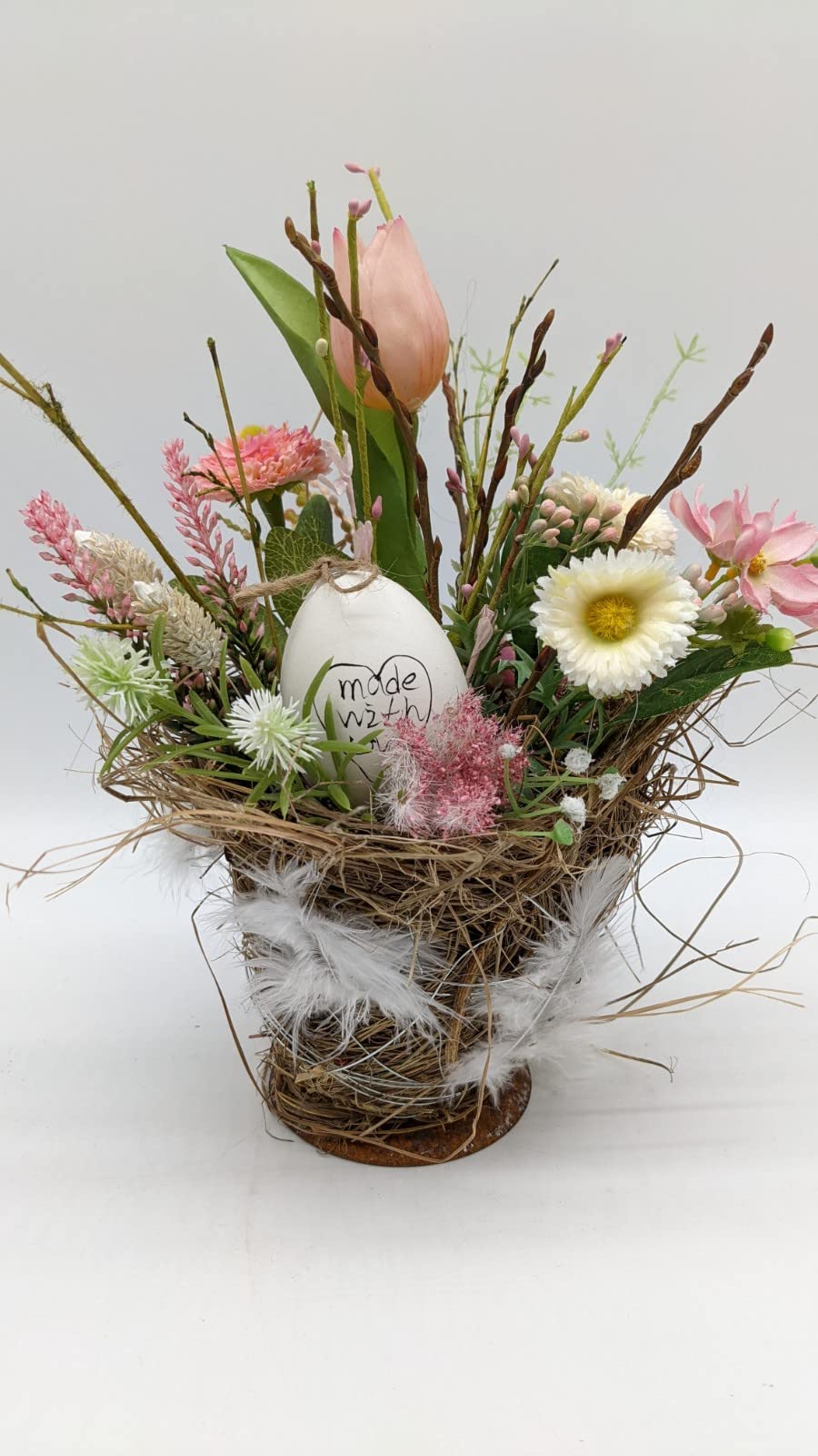 Ostergesteck im Nesttopf mit rosa Tulpe, weißer Bellis, Ei an Kordel, Federn und Bast