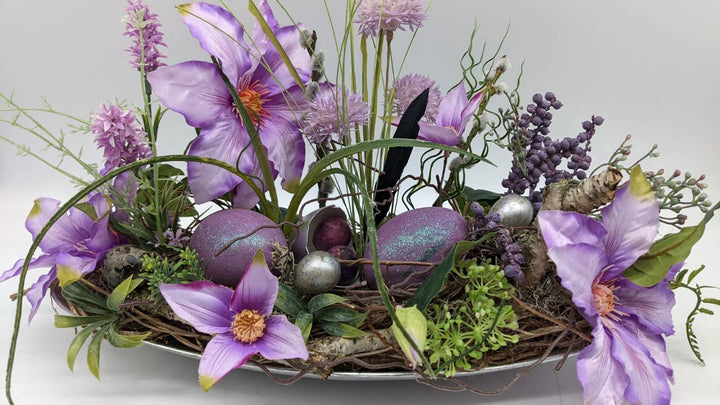 Ostergesteck Frühlingsgesteck Tischgesteck Clematis Wiesenblumen Eier Feder Gräser lila silber