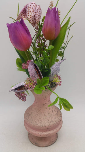 Frühlingsgesteck mit lila Tulpen, Schachbrettblume und Schoten in rosa gesprenkelter Vase mit geschwungenem Fuß