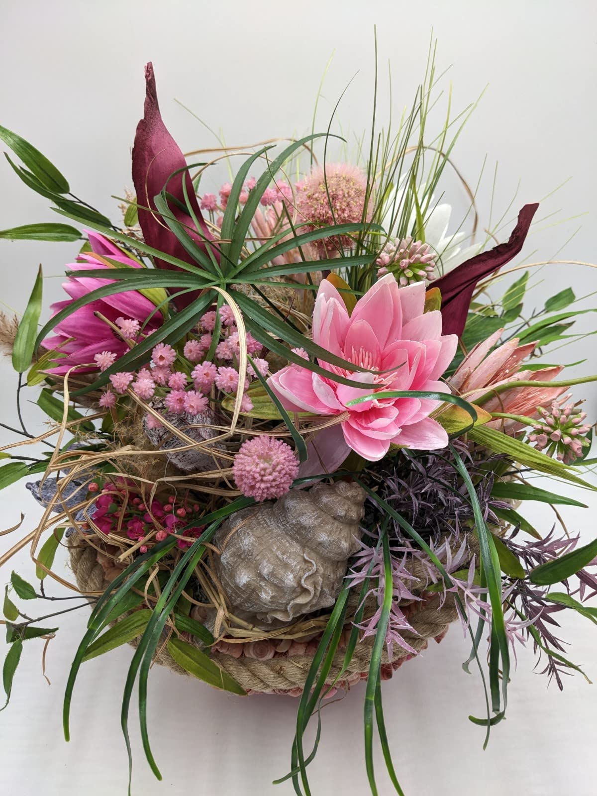 Tischgesteck in Rosa und Grün mit Seerose, Blütenbällchen, Beeren und Kordelschale seitlich fotografiert