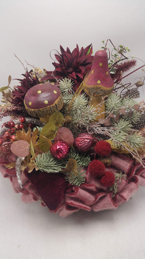 Nahaufnahme des Herbstgestecks mit goldgepunkteten Pilzen, Glas-Nüssen, roten Beeren und Eukalyptusblättern