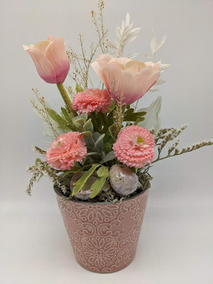 Ostergesteck mit rosa Anemonen, Bellis und gesprenkelten Eiern in altrosa Keramiktopf mit Ornamentmuster