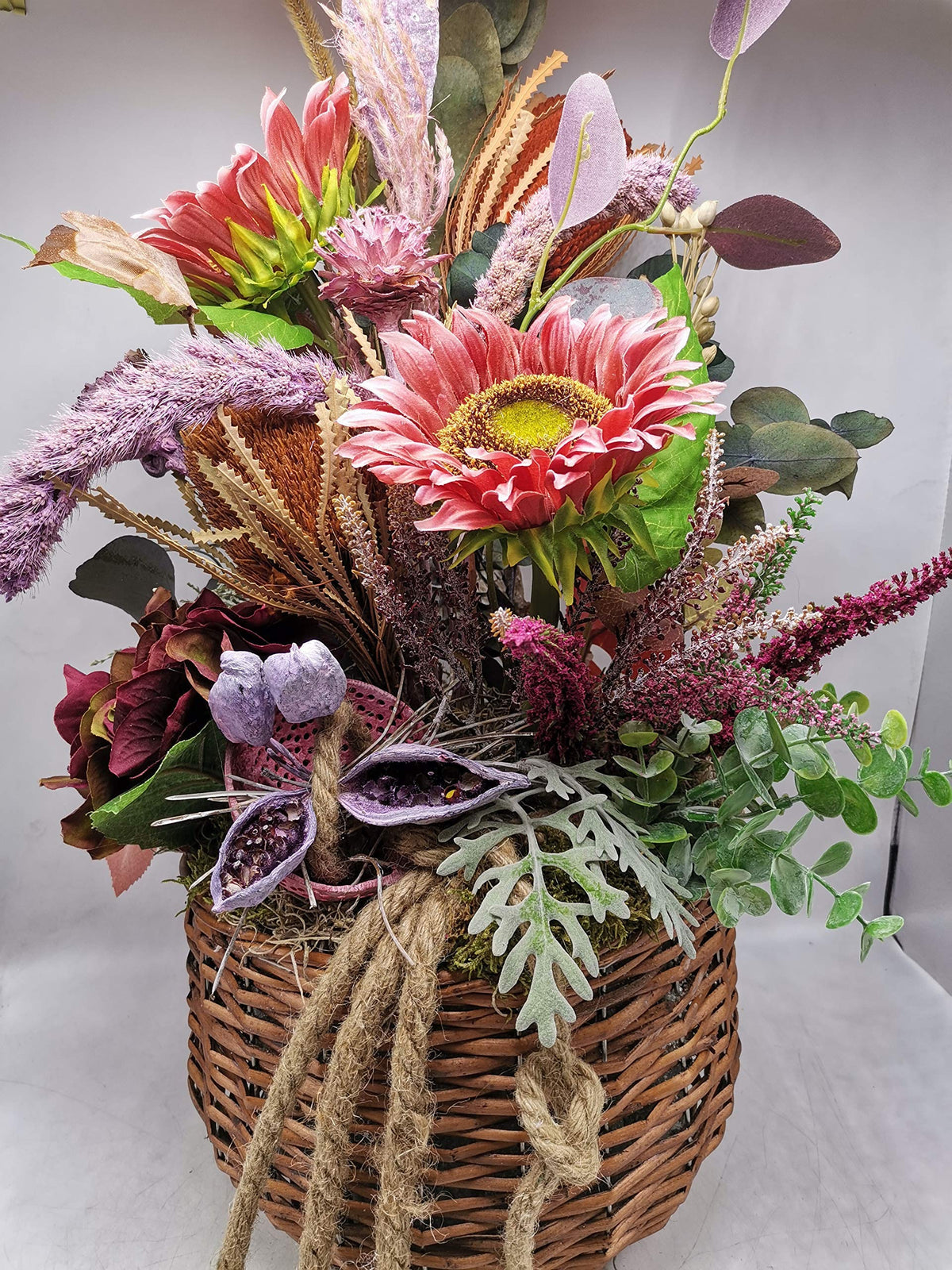 Detail des Herbstgestecks: rosa Sonnenblume mit gelber Mitte, weinrote Hortensie und Naturkordel am Korb