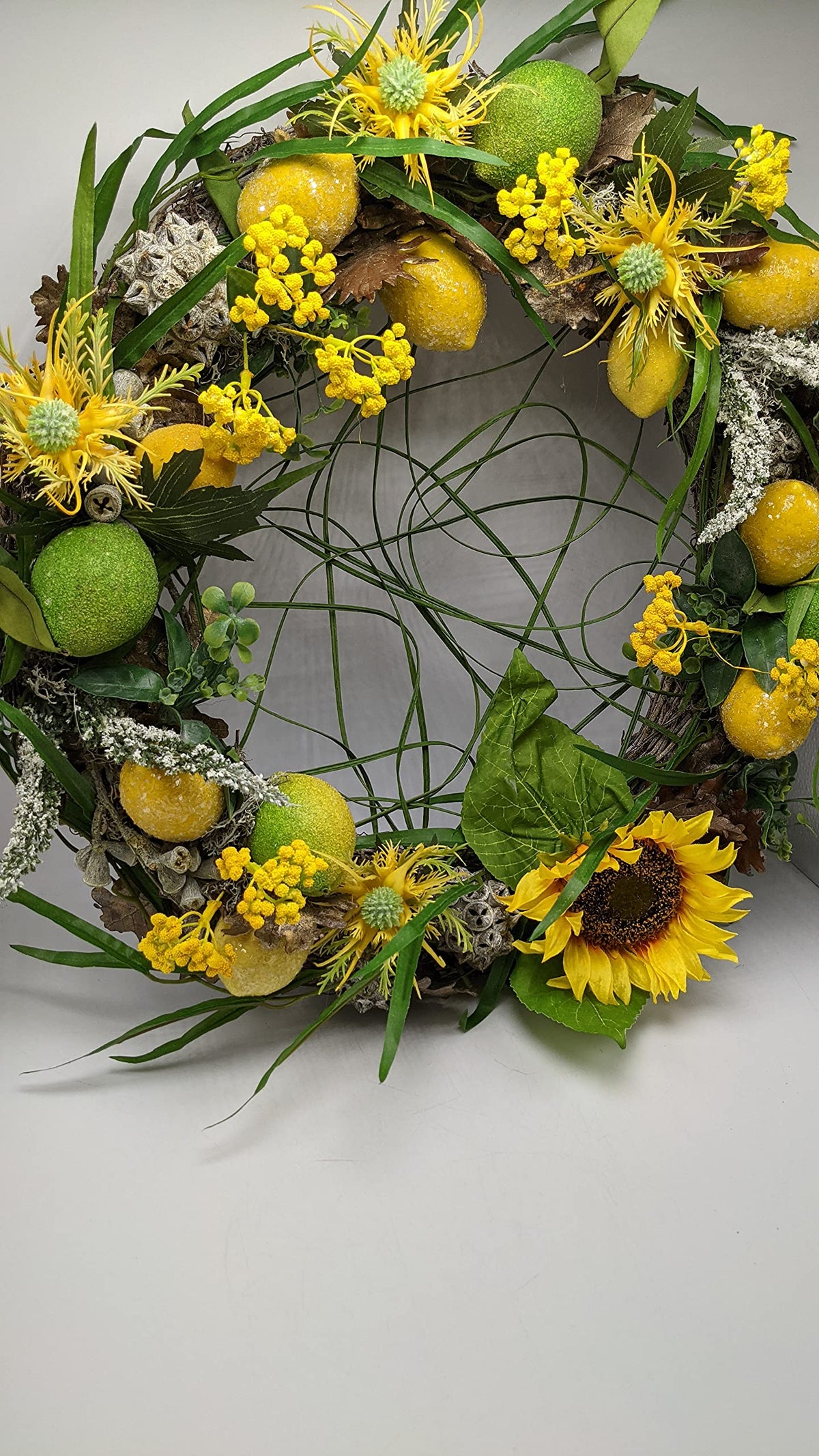 Türkranz in Gelb und Grün mit Zitronen, Limonen, gelben Blütendolden und offener Mitte aus Grashalmen