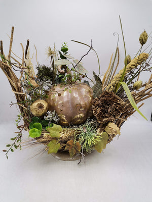 Herbstgesteck seitlich: Kürbis in Altrosa-Gold, Sedumdolde, Weinlaub und Hirse auf flacher Metallschale